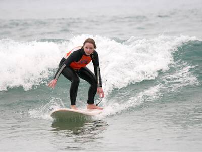 Young woman surfing a wave in Tamraght  during surf lessons with Original Surf Morocco