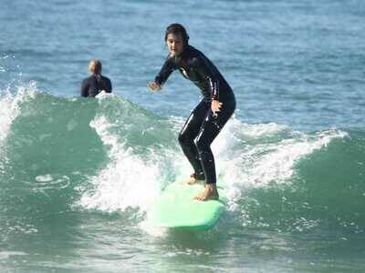 Young woman surfing a wave at Taghazout Bay during surf lessons with Original Surf Morocco