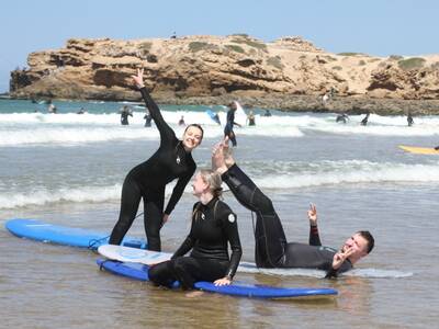 Three surfers laughing with surfboards on the beach in Tamraght, Morocco with Original Surf Morocco