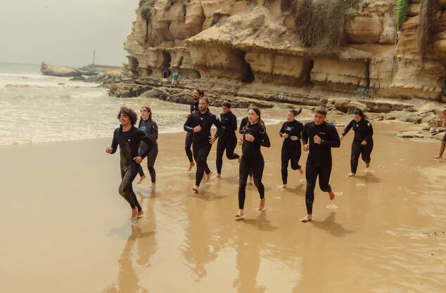 Surfers running to the ocean in Tamraght, Morocco