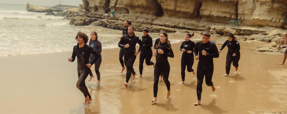 Surfers running to the ocean in Tamraght, Morocco