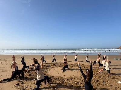 group enjoying warm-up exercises on the beach before surfing 